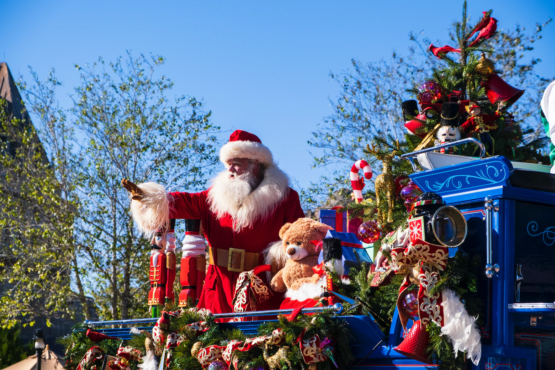 Santa Claus waving atop a sleigh filled with toys and presents
